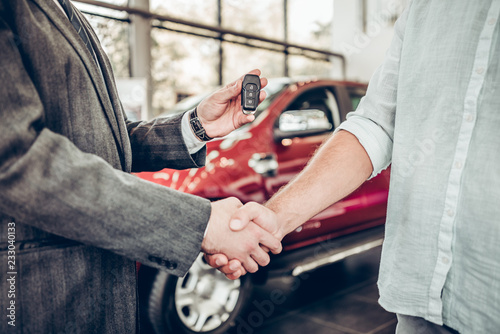 Obraz na plátně Handshake and handing over the keys to the car by the salon consultant to the buyer