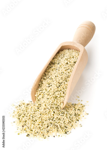 Heap of raw, organic hemp seeds on wooden scoop over white