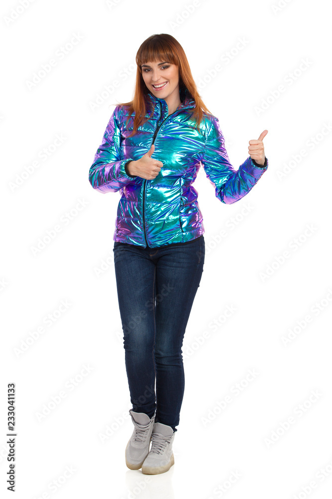 Young Woman In Vibrant Down Jacket Is Smiling And Showing Thumbs Up Young Woman In Vibrant Down Jacket Is Smiling And Showing Thumbs Up
