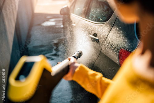 Woman washing her car with pressure washer