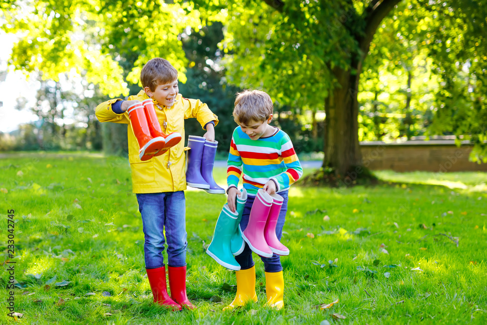 Two little kids boys, cute siblings with lots of colorful rain boots.  Children in different rubber boots and jackets. Footwear for rainy fall.  Healthy twins and best friends having fun outdoors Photos