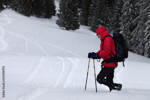 Hiker with ski poles makes his way on off-piste snowy slope