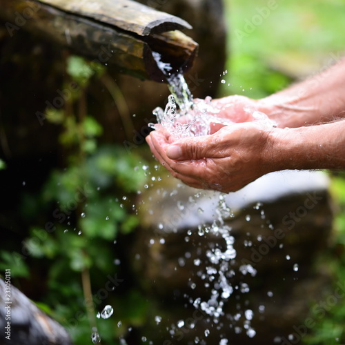 man washing hands in fresh, cold, potable water of mountain spring
