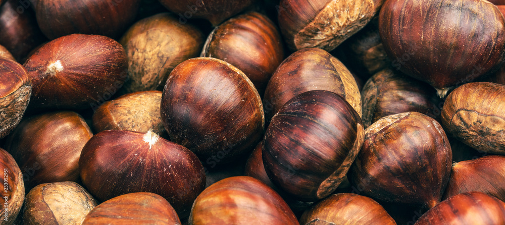 Obraz premium Roasted chestnuts served in chestnut pan on an old table