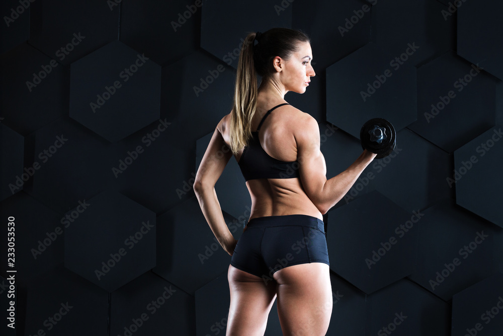 Sporty beautiful woman doing fitness gym exercising on a dark background.