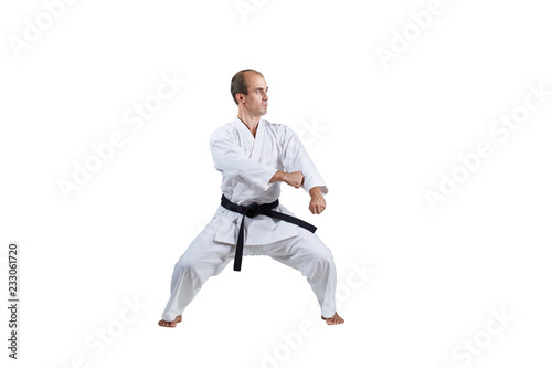Adult active athlete doing formal karate exercises on a white background