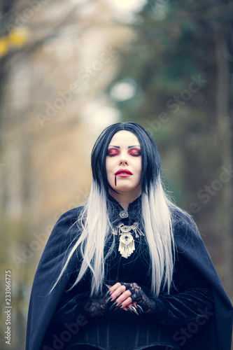 Photo of vampire woman with eyes closed with blood at mouth