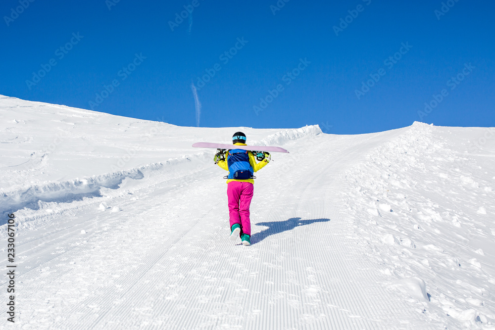 Photo from back of female athlete with snowboard on shoulders