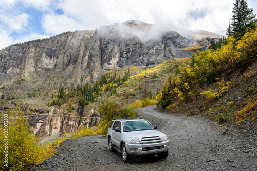 Fényképezés Exploring Autumn Mountains - On a cloudy and foggy autumn day, a 4X4 SUV is exploring in colorful autumn mountains on winding Black Bear Pass trail, near Telluride, CO, USA
