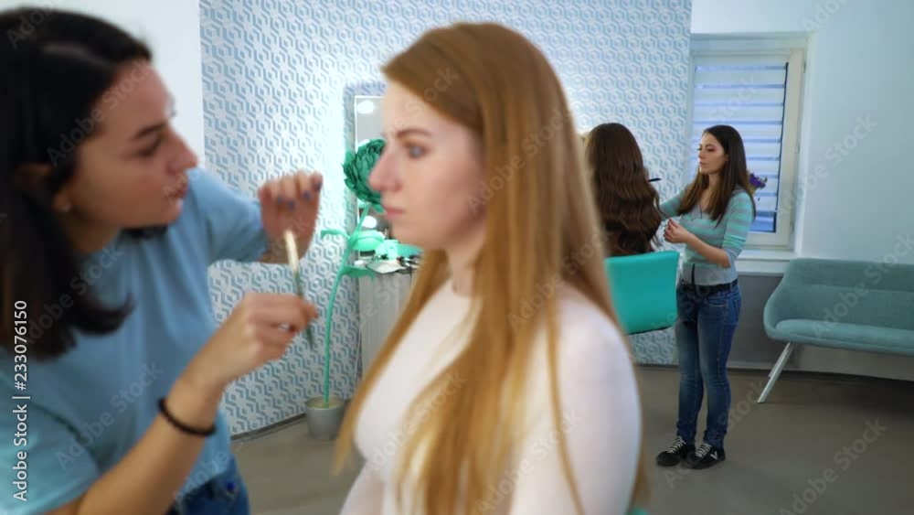 panning shot of beauty salon girls doing professional makeup and hairstyle for young women. people, cosmetics, care, lifestyle, style concept panning shot of beauty salon girls doing professional makeup and hairstyle for young women. people, cosmetics, care, lifestyle, style concept