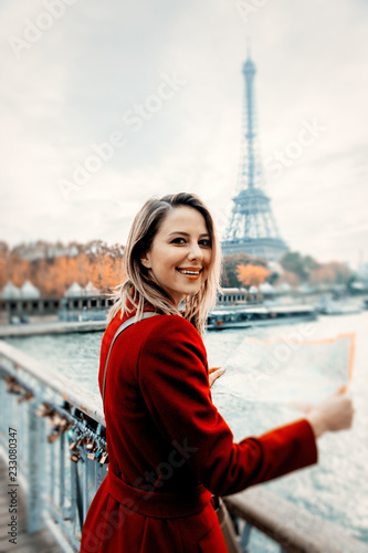 Style redhead girl in red coat with map at parisian street in autumn season time. Eiffel tower on background