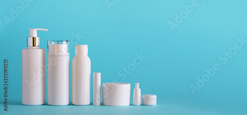 White cosmetic tubes on blue background with copy space. Skin care  body treatment  beauty concept. Banner