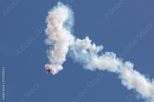Biplane at the aerobatic show with big white smoke trail