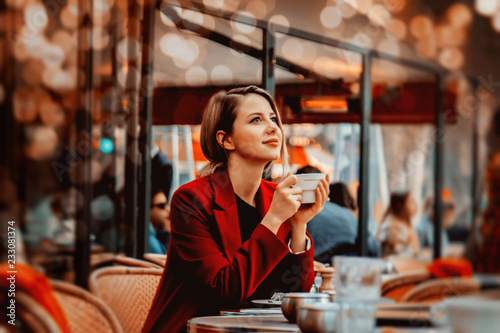 Style redhead girl in red coat with cup of coffee in parisian cafe. Autumn season time © Masson
