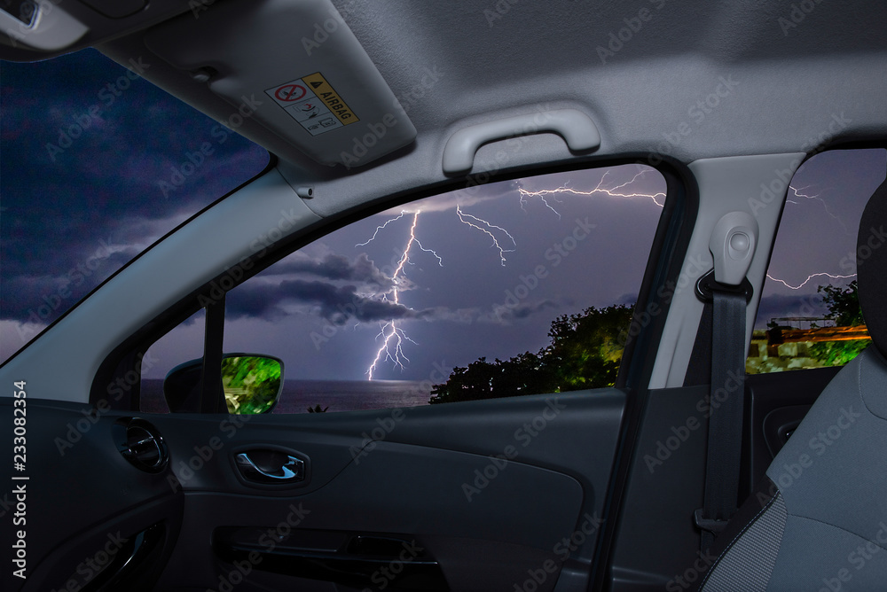 Car window with view of lightning storm over the sea