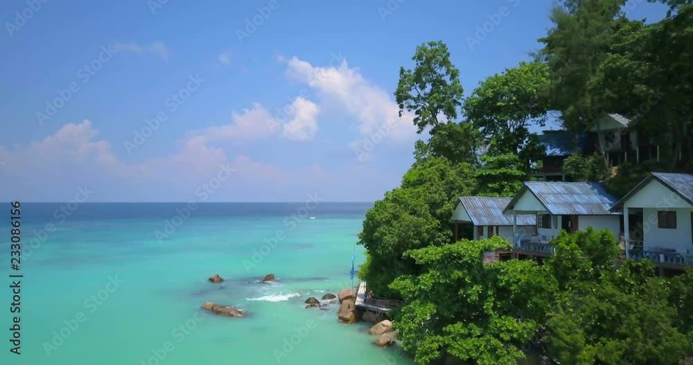 Slow ascending forward advancing aerial drone view of beach, rocky coast passing bungalows and forest toward Andaman sea on tropical island Ko Lipe, Thailand. 4k 1.9:1 23.976fps