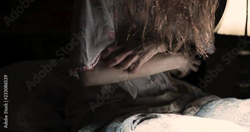 Scary girl obsessed by devil scratches in convulsions on the bed / exorcism concept / detail photo