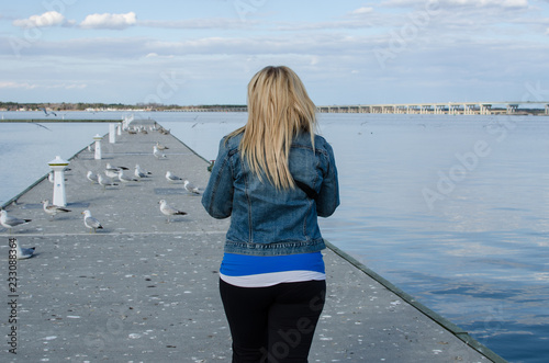 Young adult woman walks out onto a pier near the Choptank River in Cambridge Maryland on a sunny spring day photo