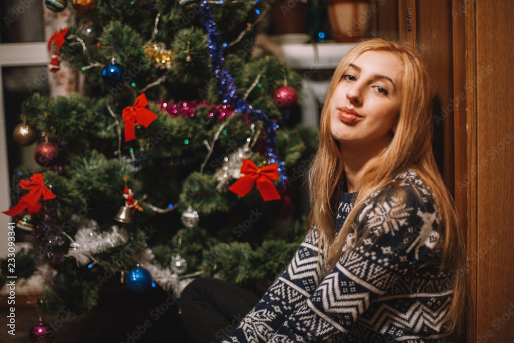 Young woman sitting beside Christmas tree