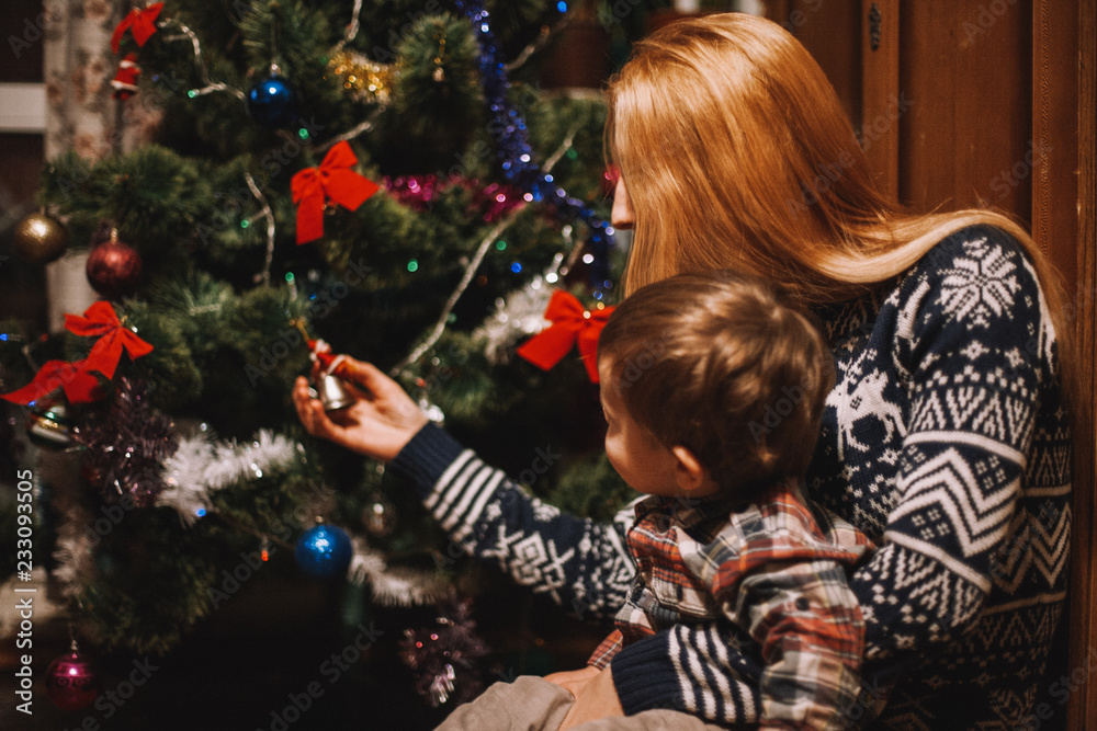 Mother and son sitting beside Christmas tree at home