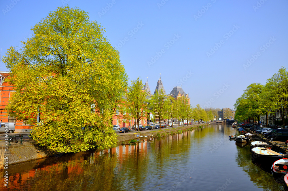Beautiful river canal with boats and green trees in Amsterdam, Holland (Netherlands)