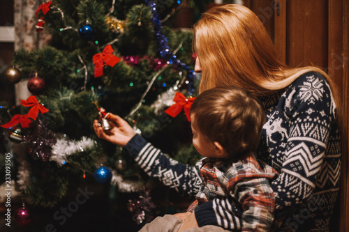 Mother and son sitting beside Christmas tree at home