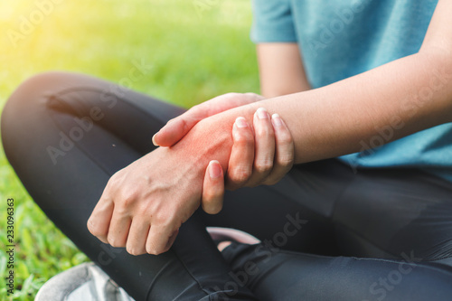 Young woman asian have accident and holding her wrist pain twist sprain in sport exercise jogging, selective focus. photo