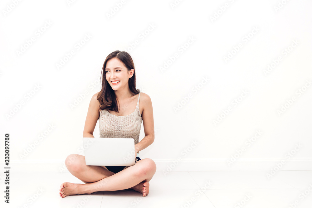 Beautiful woman using digital laptop computer checking social apps and working sitting on the floor against copy space for adding text with white wall background.wireless technology concept Beautiful woman using digital laptop computer checking social apps and working sitting on the floor against copy space for adding text with white wall background.wireless technology concept