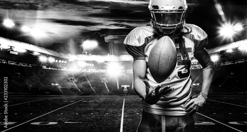 American football player, athlete in helmet with ball on stadium. Black and white photo. Sport wallpaper with copyspace.