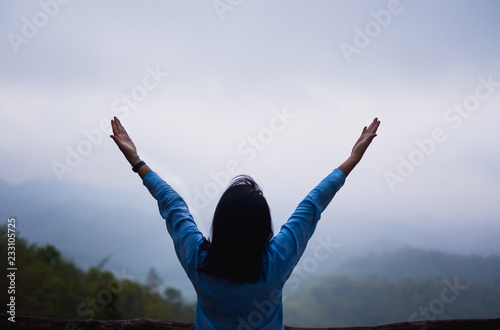 Asian woman arms up at mountain natural view point with fog in morning.freedom lifestyle travel concept.