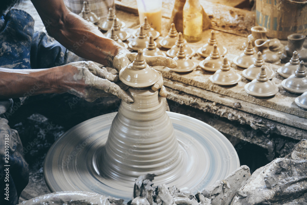 close up professional potter's hand making Thai style pot lid on a potter's wheel in pottery villages at Ko Kret, Nonthaburi province, Thailand (selective focus) close up professional potter's hand making Thai style pot lid on a potter's wheel in pottery villages at Ko Kret, Nonthaburi province, Thailand (selective focus)