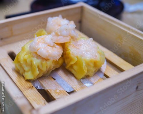 The​ shrimp chinese steamed dumpling​ in​ Dim Sum wooden steamer on​ the​ table​ which​ it is in a Chinese restaurant. photo