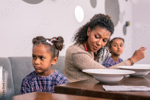 Emotional daughter. Cute dark-eyed daughter feeling emotional and offended while having lunch with mom