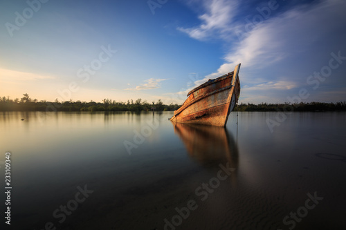 Abandon Old wreck on the shore   Borneo   Old fishing boat with the reflection on sunset moment