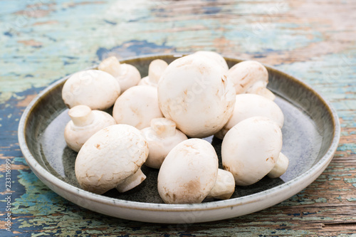 Fresh mushrooms in a plate on an old wooden table. Rustic style