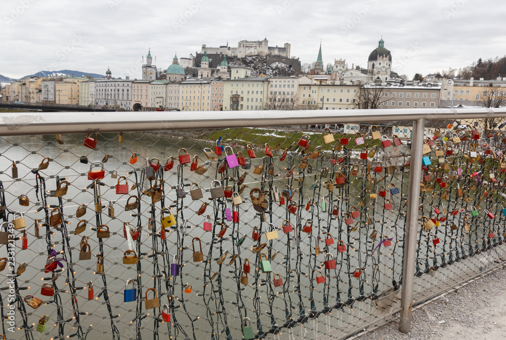 Naklejka premium panoramic winter view of the historic center of Salzburg Austria surrounded by the Alps covered with snow in a foggy haze from the bridge with padlocks