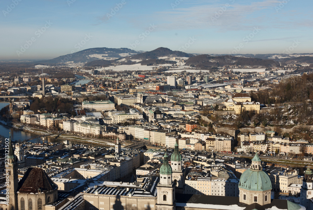 panoramic winter view of the historic center of Salzburg Austria surrounded by the Alps covered with snow in a foggy haze