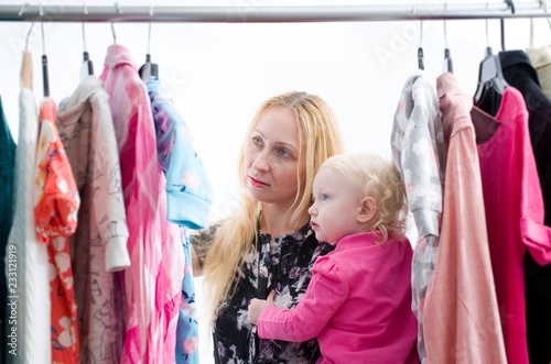 Woman with baby chooses clothes in the wardrobe closet at home