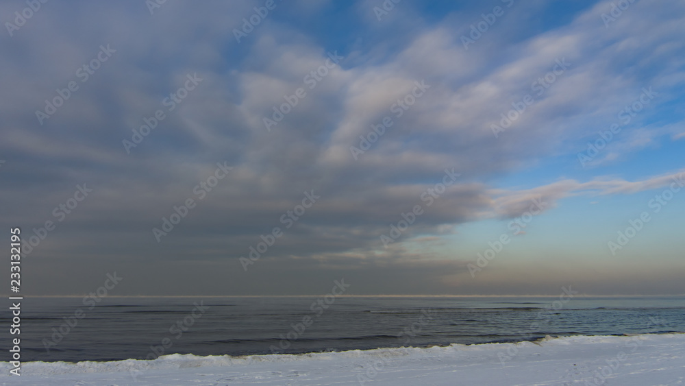Winter shoreline of baltic sea with snow and ice under blue sky with clouds, selective focus