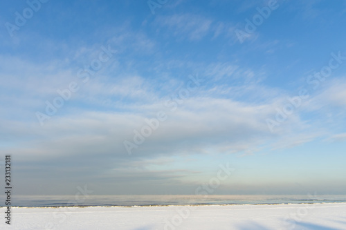 Winter shoreline of baltic sea with snow and ice under blue sky with clouds, selective focus