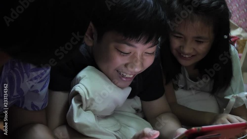Asian children playing with a tablet cpmputer at home .Recorded hand-held in slow motion at 4K at 60fps.