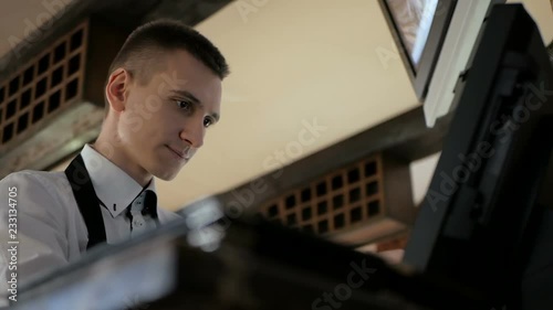 Man or waiter in apron at counter with cashbox working at the restaurant
