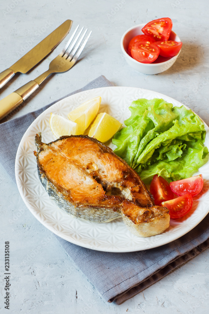 Steak baked salmon fish on a plate with fresh vegetables.