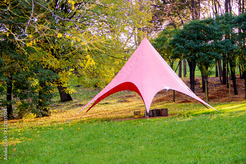 Pink tent in the woods on the green grass on a sunny day