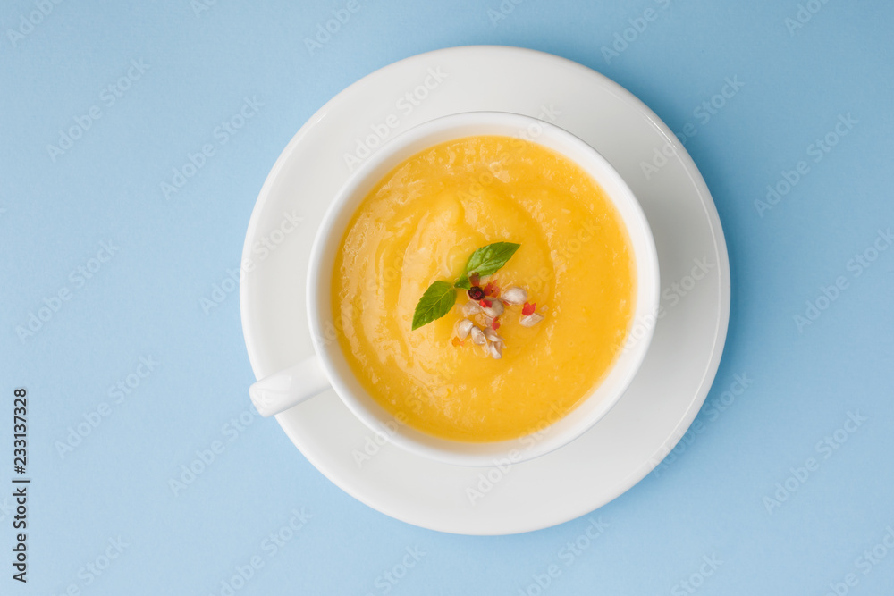 Pumpkin soup mashed with spices in a Cup on a blue background. Pumpkin soup mashed with spices in a Cup on a blue background.