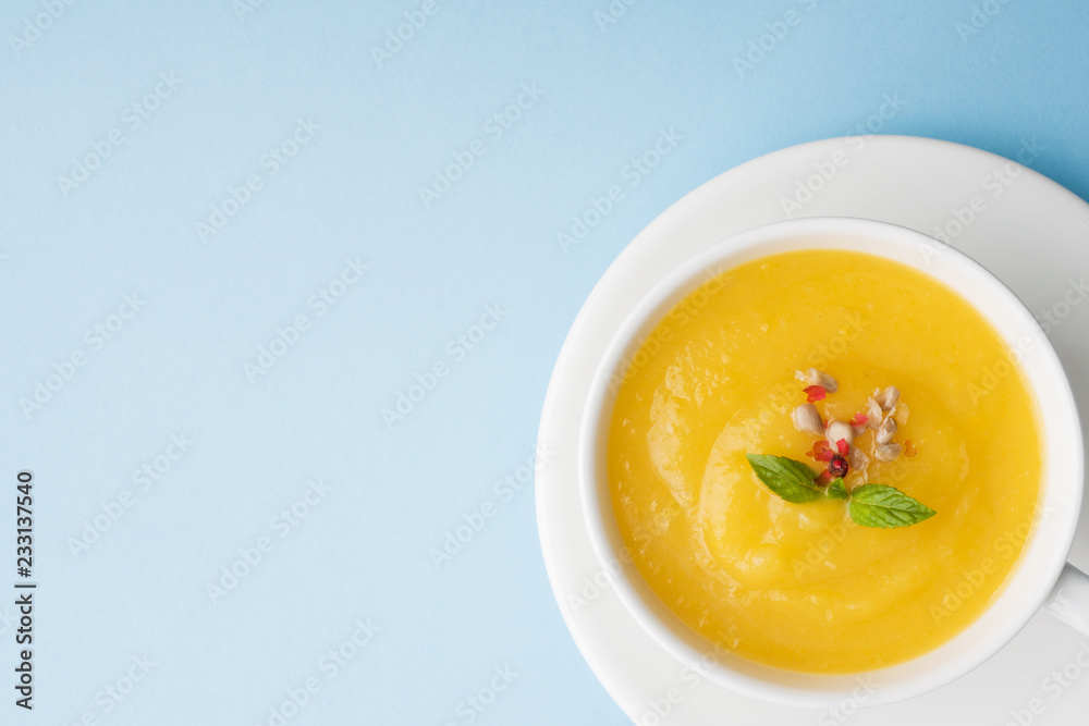 Pumpkin soup mashed with spices in a Cup on a blue background. Pumpkin soup mashed with spices in a Cup on a blue background.
