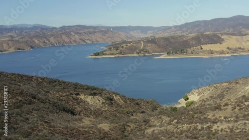A blue lake in between hills with power boats and kayaks