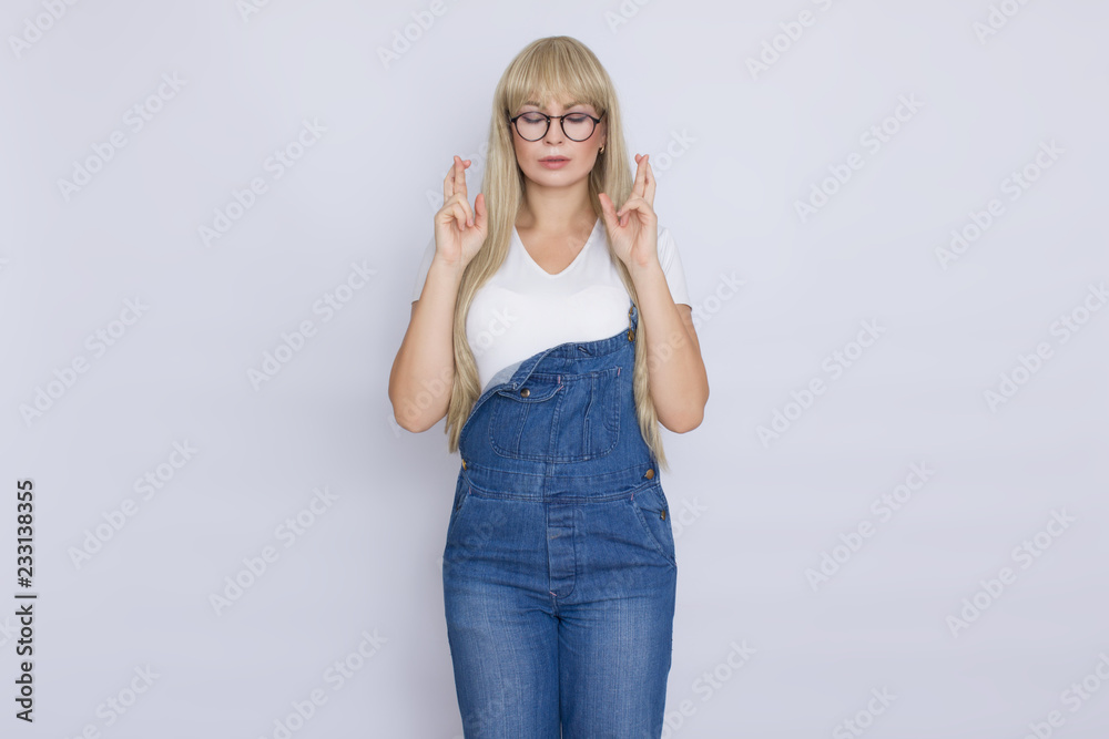 Young blond woman in jeans overalls and glasses