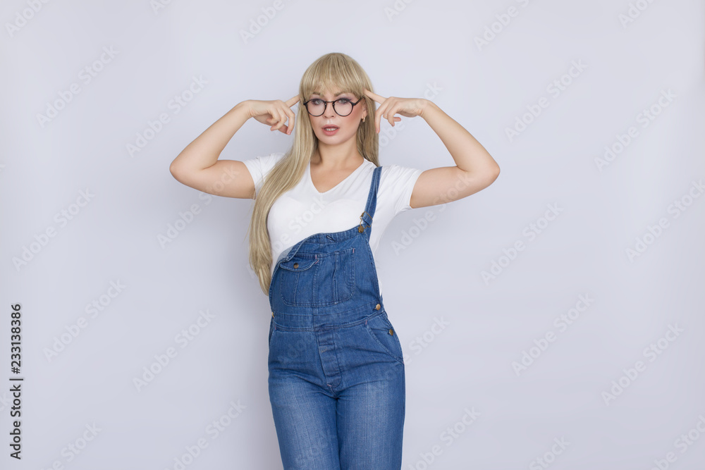 Young blond woman in jeans overalls and glasses Young blond woman in jeans overalls and glasses