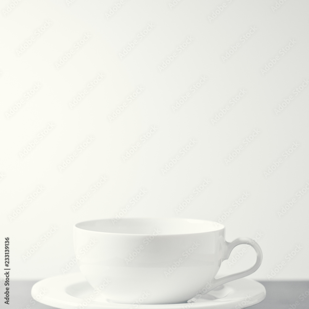 White porcelain tea cup shot against a creamy white background. With copy space. White porcelain tea cup shot against a creamy white background. With copy space.